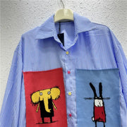 Blue striped shirt with red and blue pocket designs on a hanger against a gray wall.