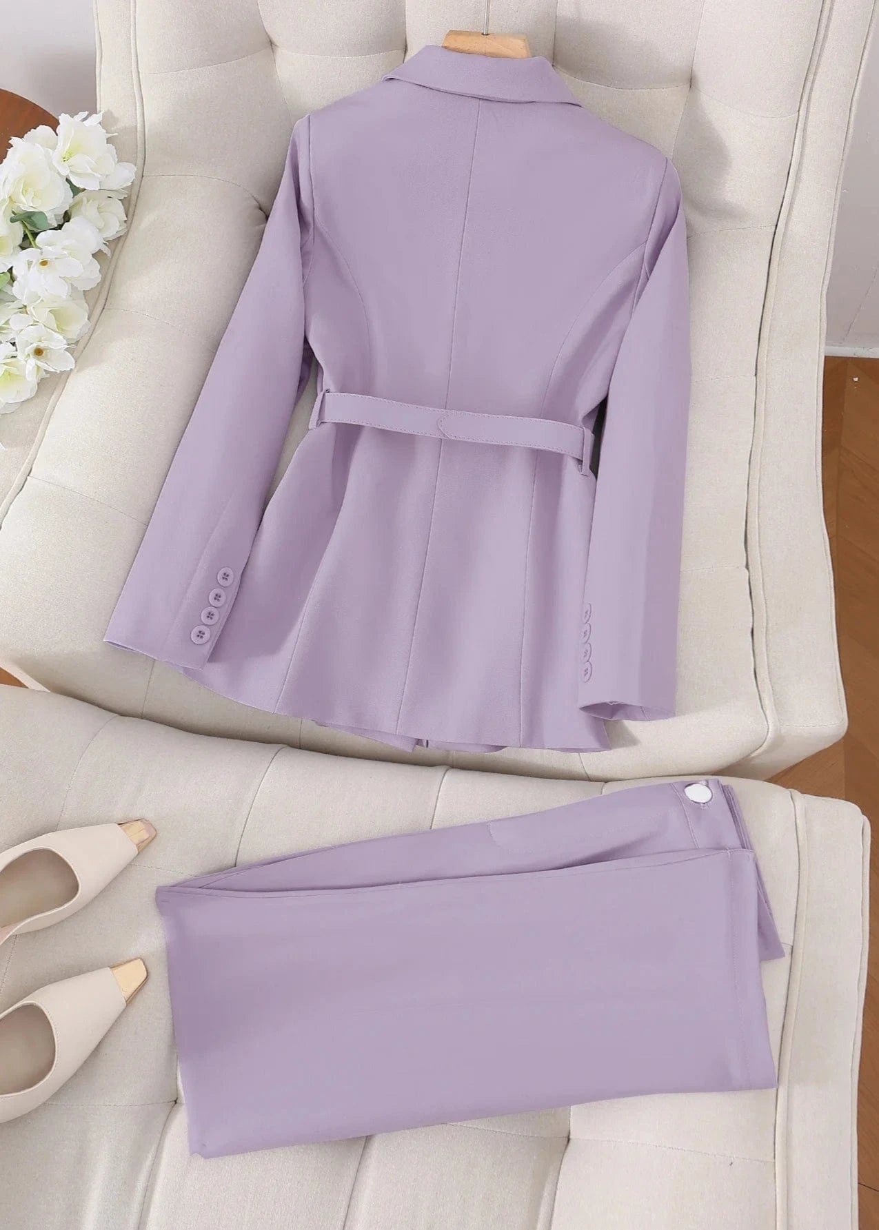Purple suit jacket and pants on a white chair with white shoes beside it.