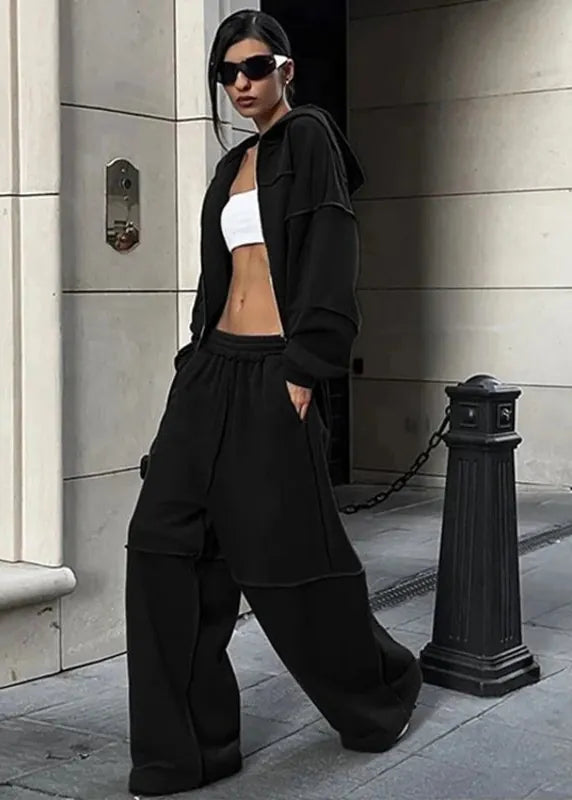 Person wearing a black outfit with sunglasses standing on a city street.
