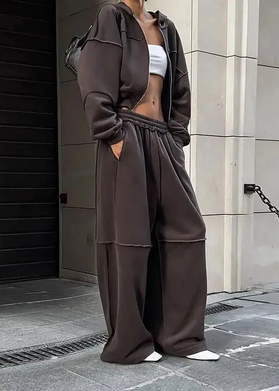 Person wearing a brown tracksuit standing on a street.