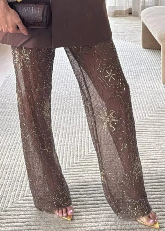 Brown pants with decorative patterns worn by a person indoors.