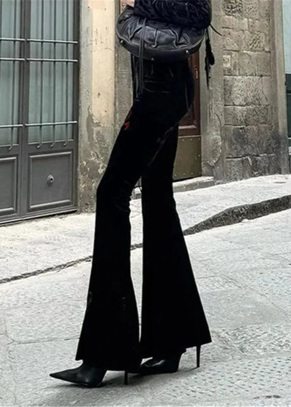 Person wearing black flared pants and high-heeled shoes on a street.