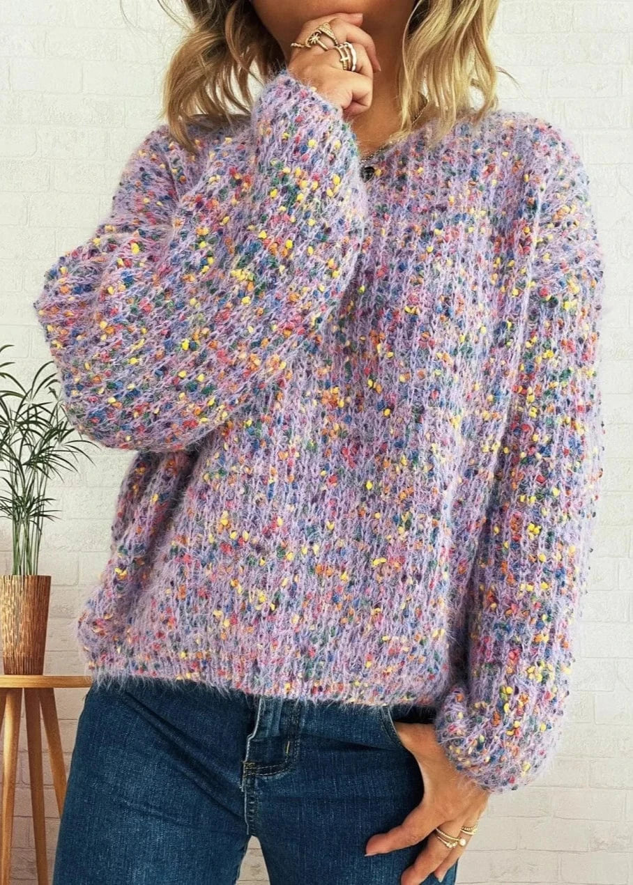 Person wearing a colorful sweater with a white wall and plant in the background