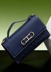 Navy blue handbag with gold clasp on a gradient green and black background