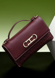 Maroon handbag with gold clasp on a green and white background