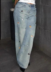 Distressed blue jeans with decorative elements on a dark tiled floor.
