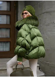 Person wearing a green puffer jacket with fur hood standing against a building.