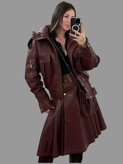 Woman taking a mirror selfie wearing a long brown leather coat in a tiled room.