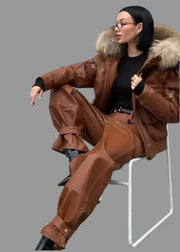 Person wearing a brown fur-lined coat sitting on a chair outdoors.