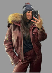 Person wearing a maroon leather jacket with fur hood taking a mirror selfie.
