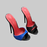 High-heeled shoes with red, blue, and black patent leather on a textured surface.