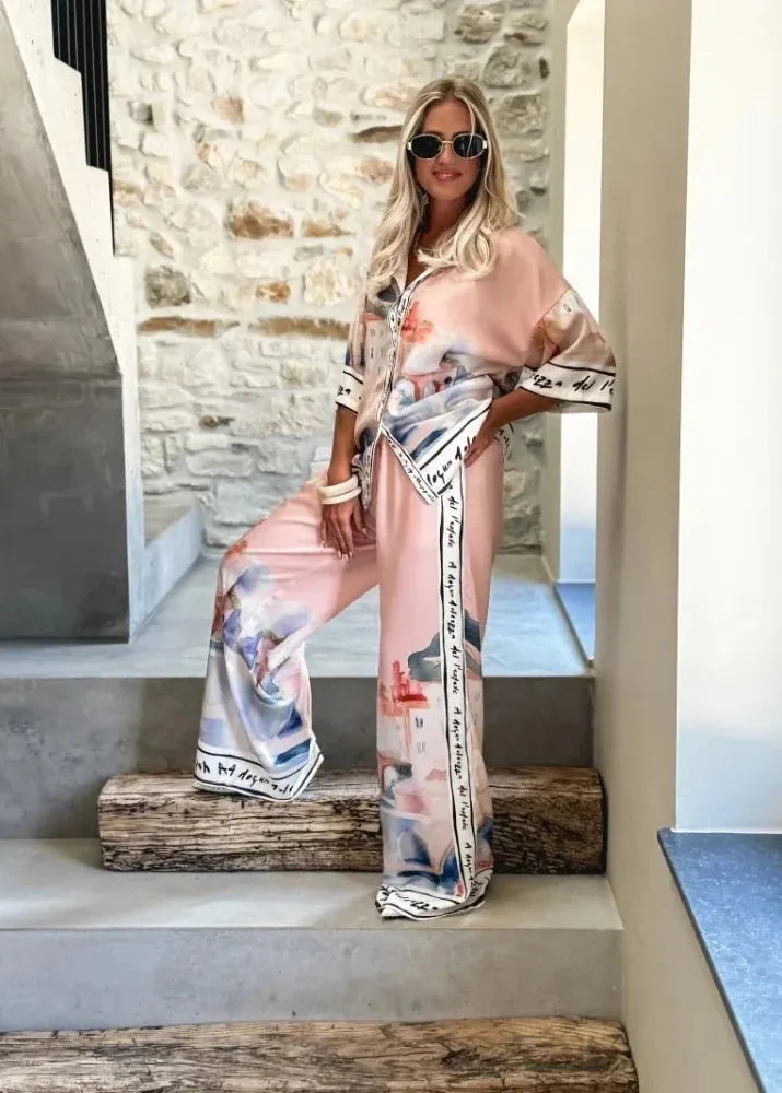 Woman in a stylish outfit with floral patterns sitting on steps.