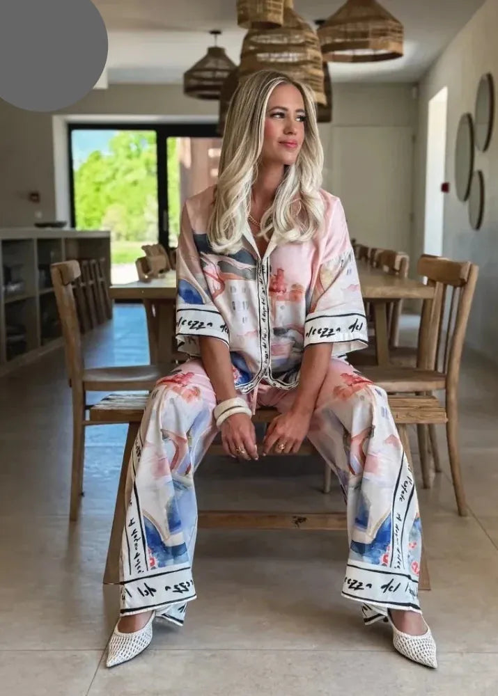 Woman sitting in a modern dining area wearing a patterned outfit.