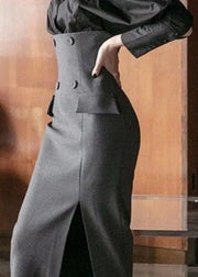 Person wearing a black outfit with a high-waisted pants and jacket against a wooden background