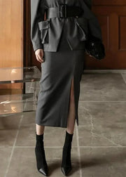 Person wearing a gray outfit with a skirt and jacket in an indoor setting.