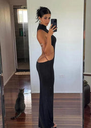 Person taking a mirror selfie wearing a black dress with cut-out design, standing in a room with a cat on the floor.