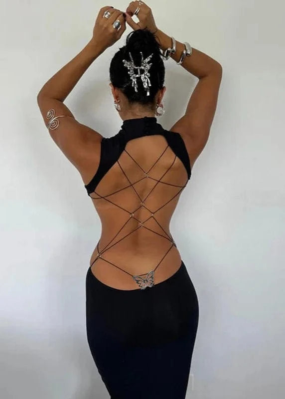 Person wearing a black dress with criss-cross back design on a plain background