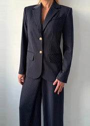 Person wearing a navy pinstripe suit against a plain background