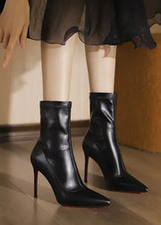 Black high-heeled boots worn with a sheer black skirt on a wooden floor.
