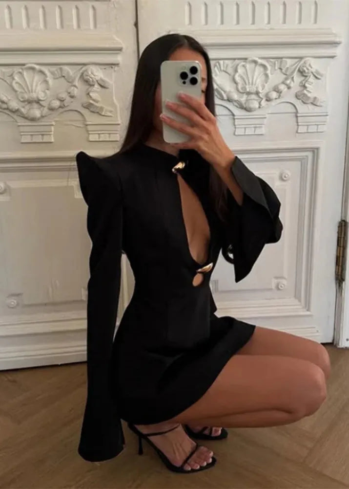 Person wearing a black dress with cut-out design in a room with decorative white wall.