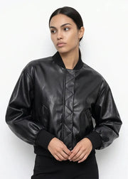 A woman wearing a black faux-leather bomber jacket with a quilted front panel and black ribbed collar, cuffs, and hem, photographed against a plain white studio background.