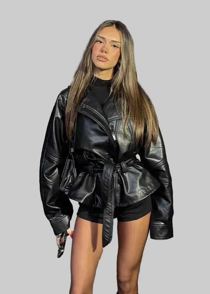Woman wearing a black leather jacket and outfit on a street.