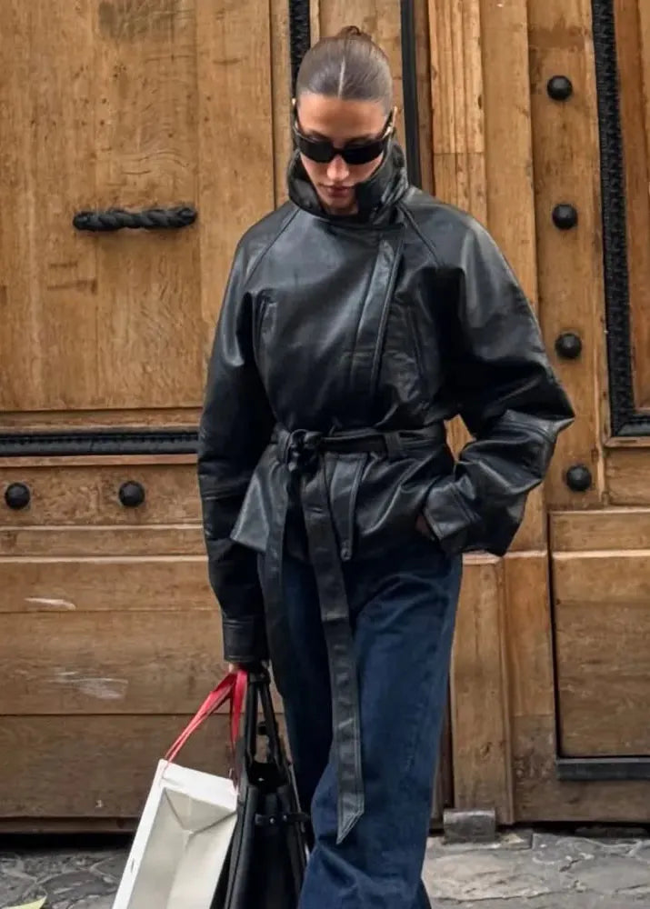 Person wearing a black leather outfit in front of wooden doors