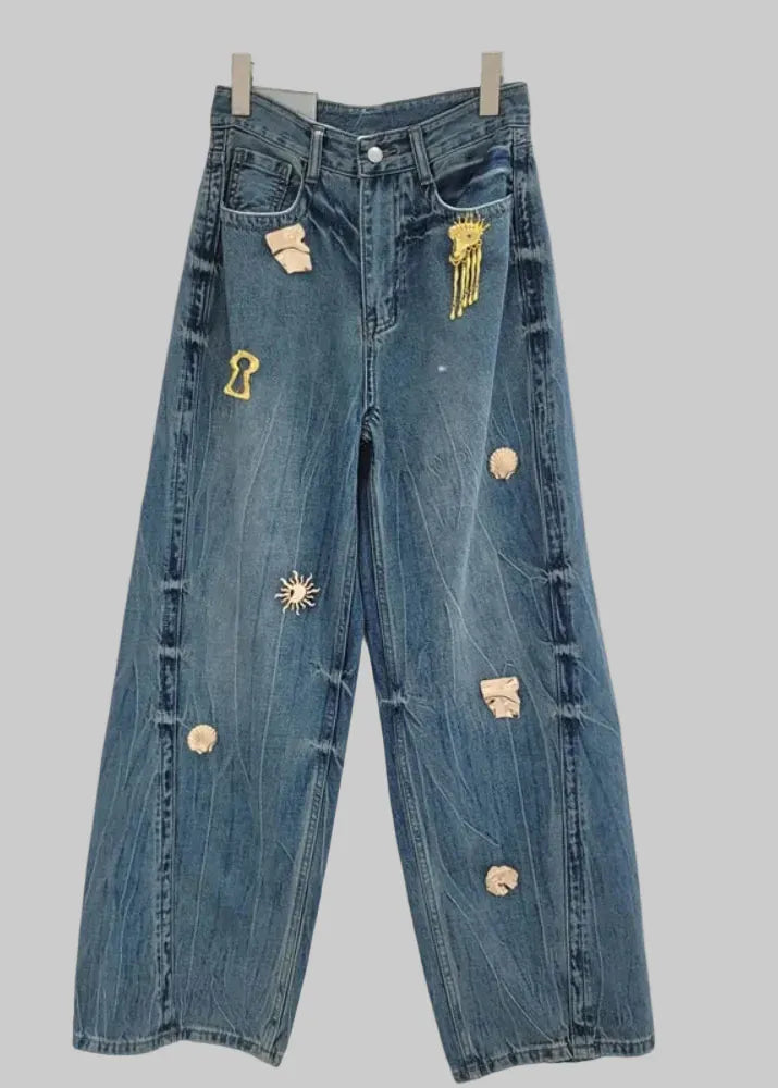 Blue jeans with decorative buttons and patches on a white background, branded 'GALCAUR'.