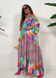 Woman wearing a colorful striped dress with a white background and green plants.