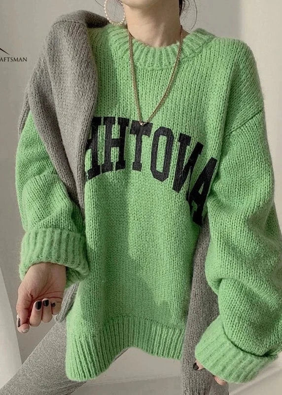 Person wearing a green sweater with text, standing against a neutral background