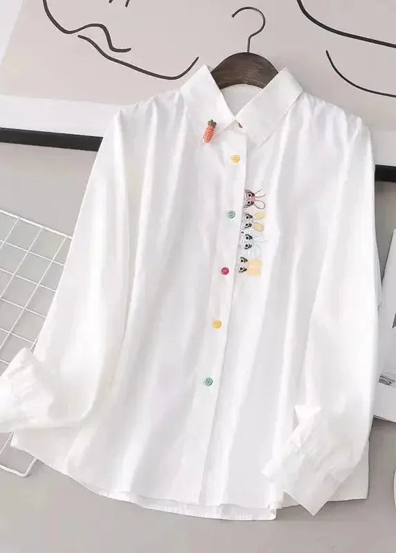 White shirt with colorful accents on a hanger against a minimal background