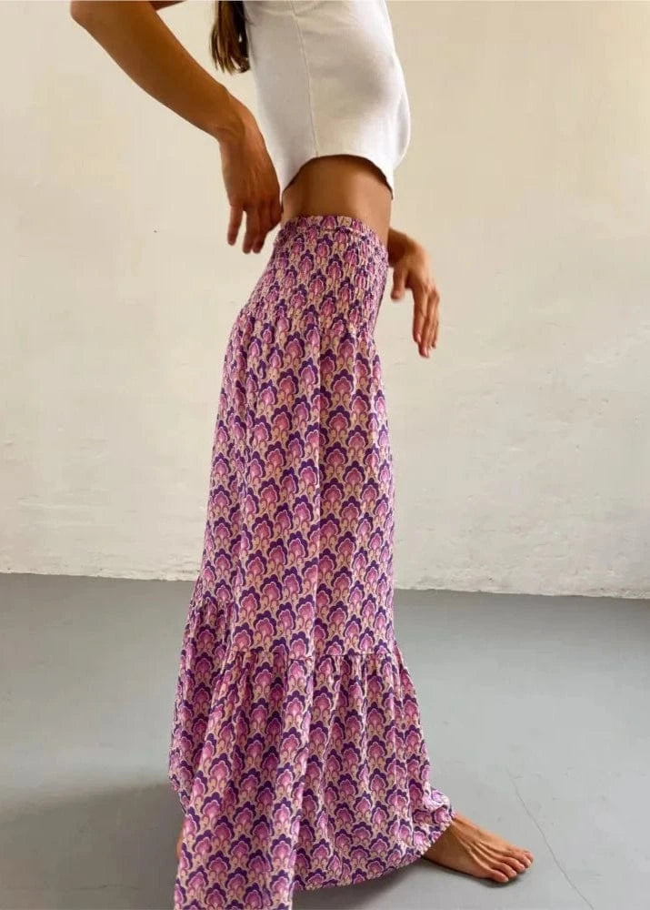 Person wearing a long, patterned skirt with a plain background