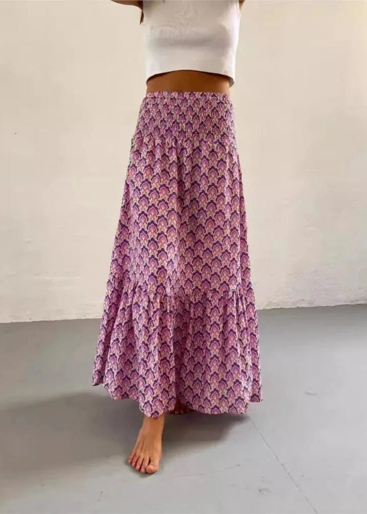 Person wearing a long purple patterned skirt on a plain background