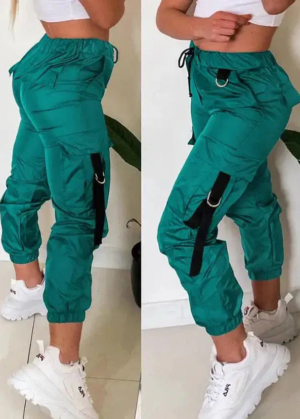Green cargo pants with black straps worn by a person on a white background