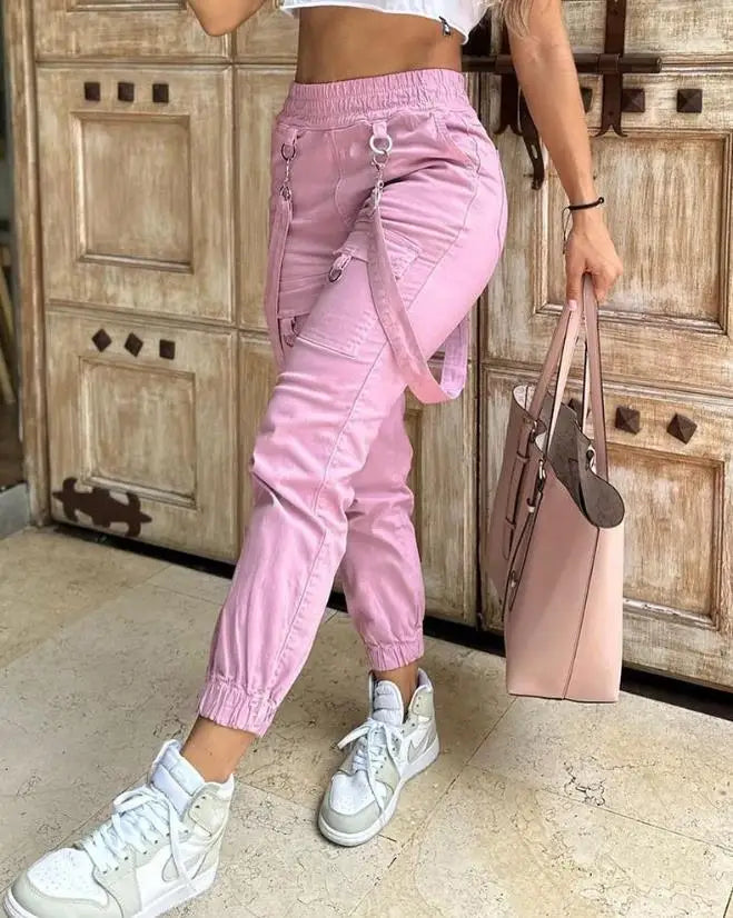 Person wearing pink cargo pants and white sneakers, holding a matching pink handbag.