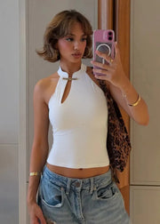 Woman taking a mirror selfie wearing a white halter top and blue jeans.