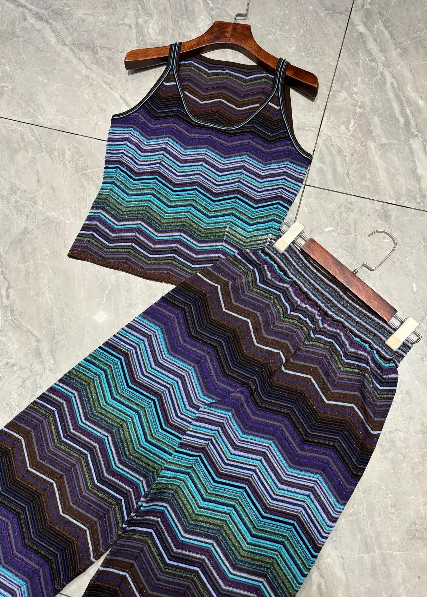 Striped tank top and leggings set on a hanger against a tiled floor background