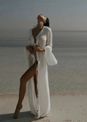 Woman in a white dress standing on a beach with ocean in the background