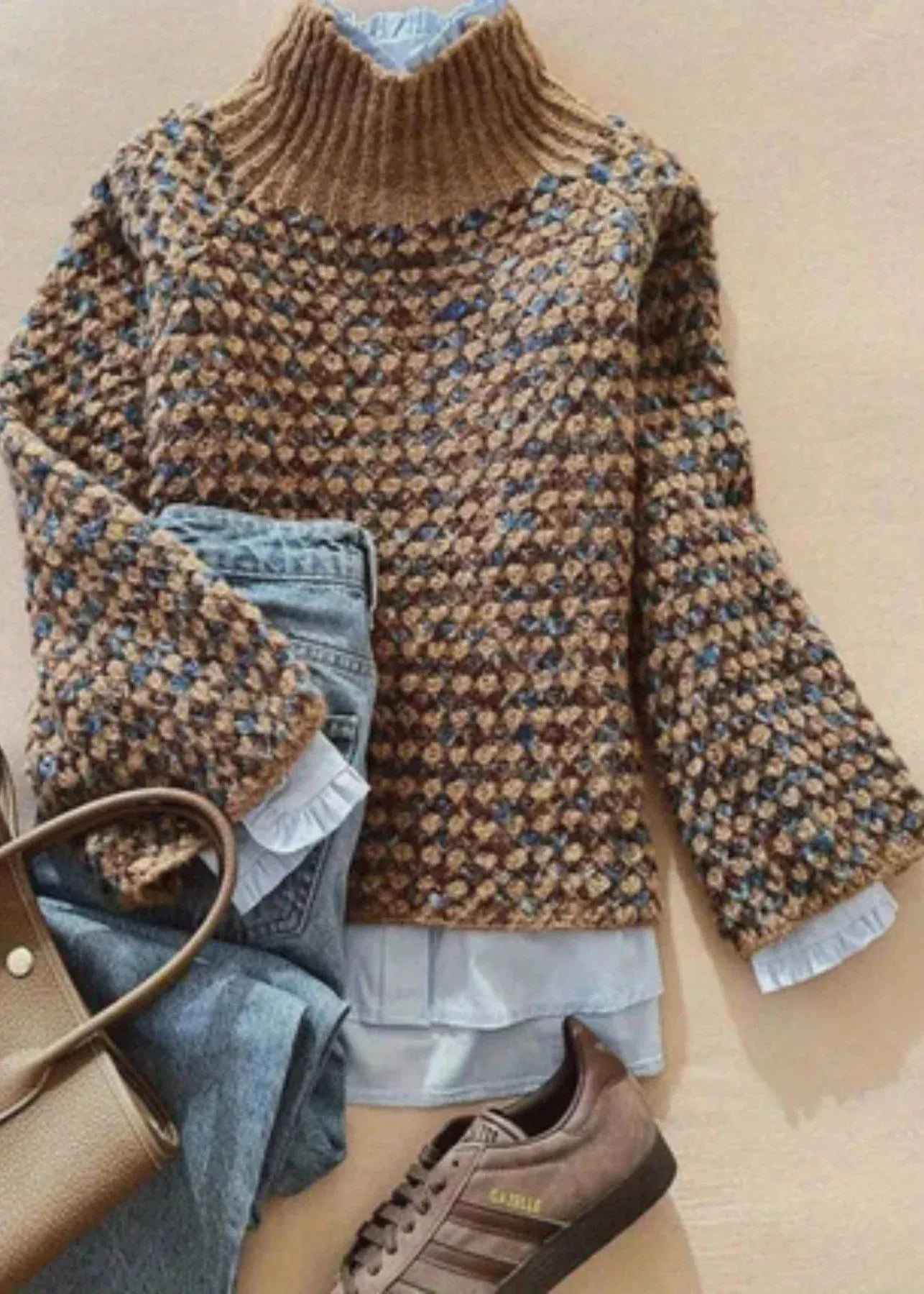 Brown patterned sweater with denim jeans and brown shoes on a beige surface