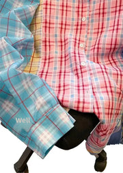 Chair with a colorful plaid shirt draped over it on a white background