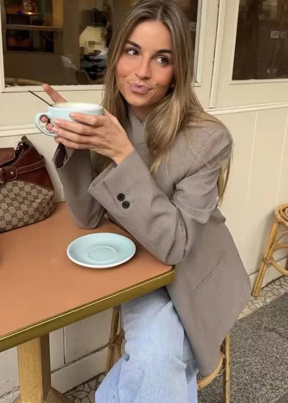 Woman sitting at a table holding a cup in a cafe setting