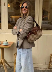 Woman holding a patterned handbag in front of a cafe.