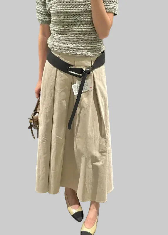 Beige skirt with black belt worn by a person, displayed on a white background.
