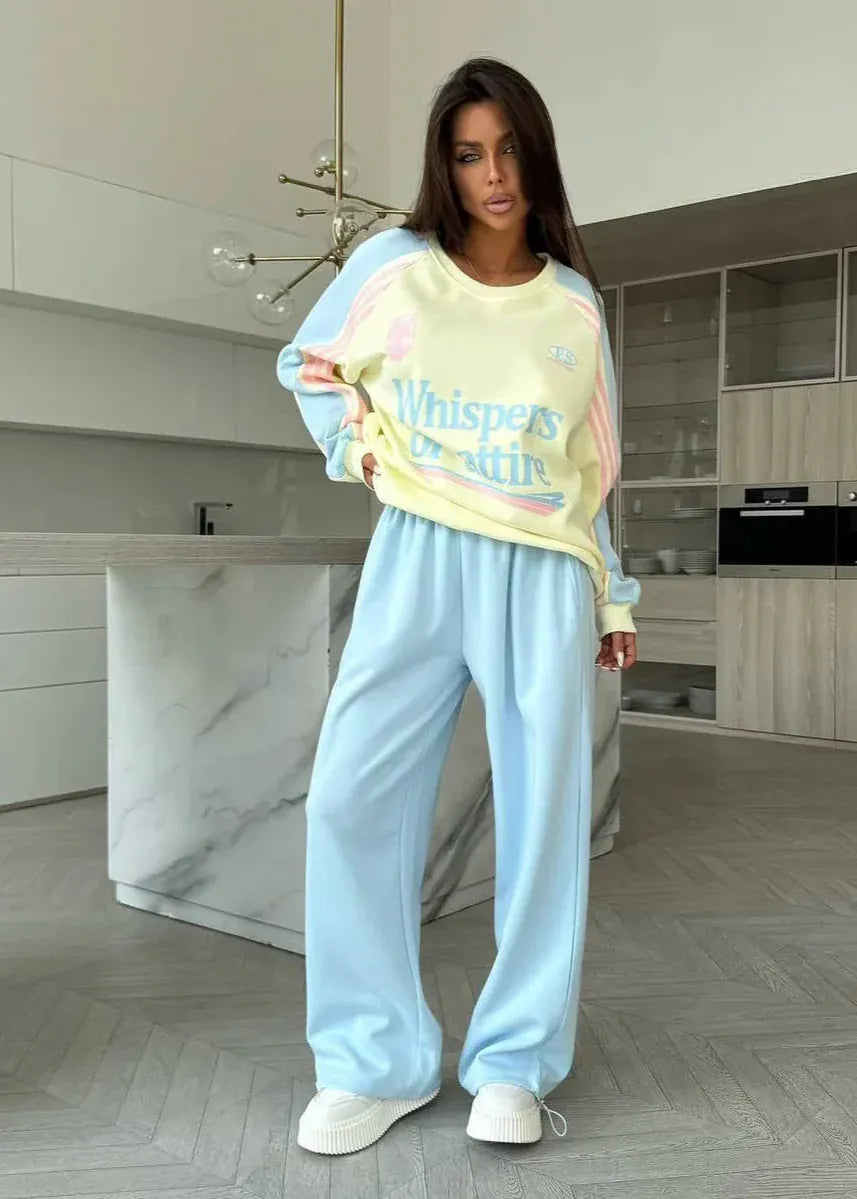 Woman wearing a pastel-colored outfit with 'Whisper' text in a modern kitchen.