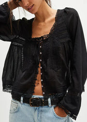 Woman wearing a black lace-up top with long sleeves and light blue jeans on a white background