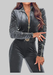 Person wearing a gray velvet outfit with a zipper on a gray background