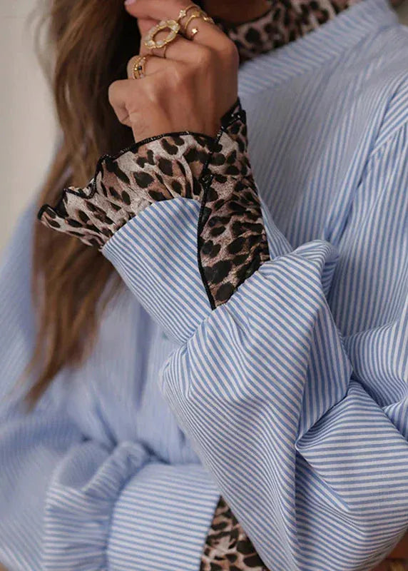 Close-up of a person wearing a blue striped shirt with a leopard print hair tie.