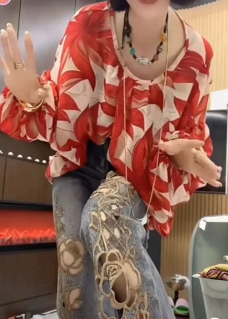 Person wearing a red and white floral blouse with a blurred background