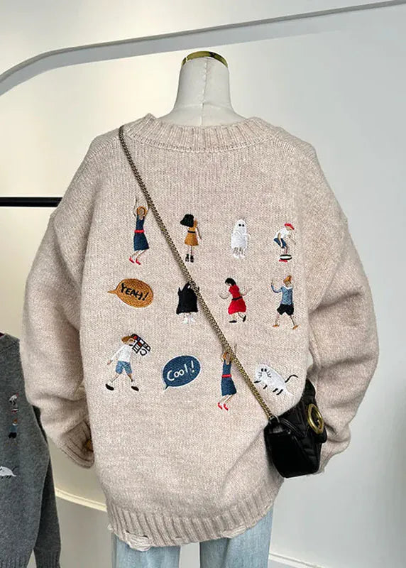Beige sweater with embroidered designs on a mannequin against a white background