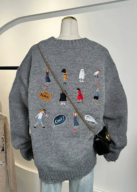 Gray sweater with embroidered designs on a mannequin against a white background